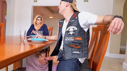 Hijab-wearing female providing a hj from under the table